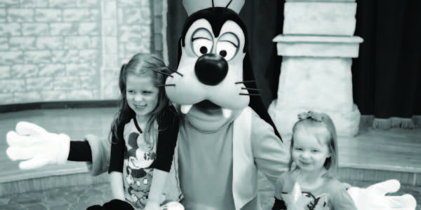 Four-year-old Lydia Hood and two-year-old sister Kiera pose with Goofy in Disneys Magic Kingdom