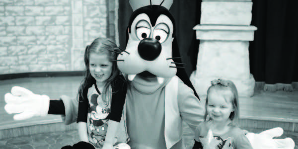 Four-year-old+Lydia+Hood+and+two-year-old+sister+Kiera+pose+with+Goofy+in+Disneys+Magic+Kingdom