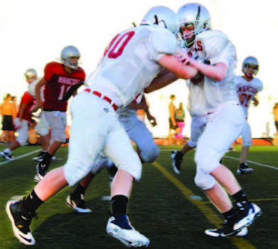 Up early in the morning, a group of junior varisty football players practice a series of playts. These plays involve defending the team quarterback and meeting an offensive team after kick-off.