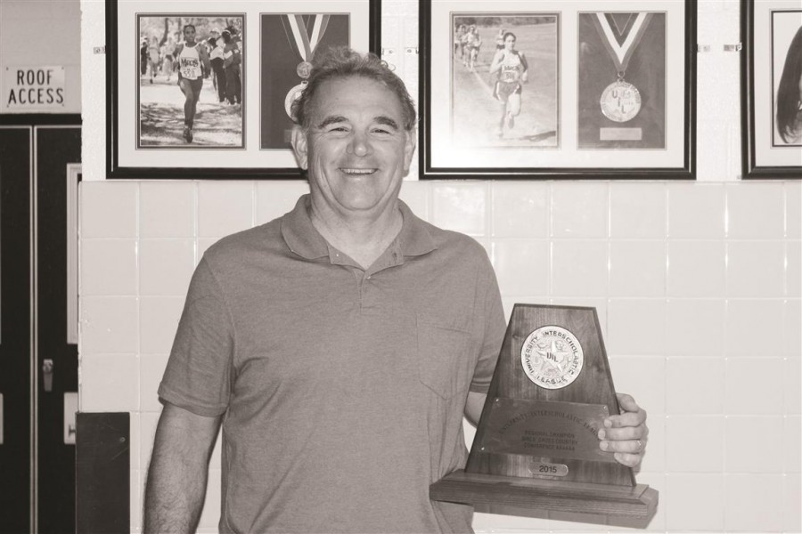 Coach Telaneus poses next to the Girls Cross Country teams regional trophy. The girls went on to win state this year after thei reginal victory. 