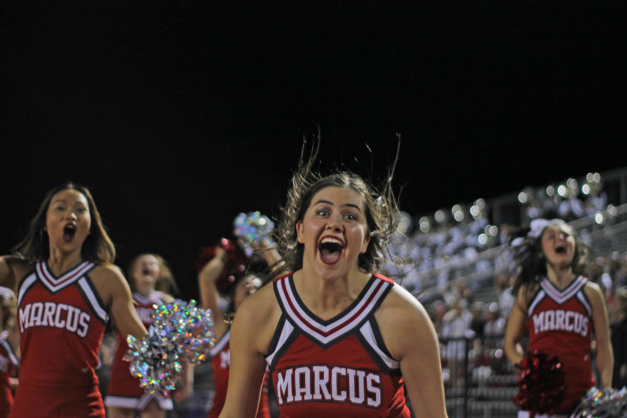 Varsity cheerleaders jump in celebration as Marcus makes a touchdown.