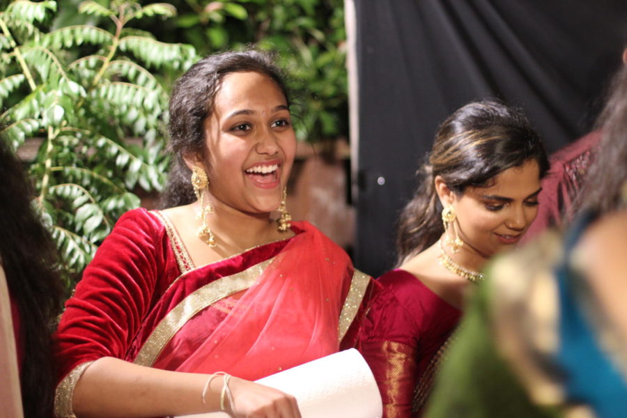 Mahima Mahavdi stands in a line with her family greeting people as she passes out various homemade Indian sweets to the guests after they all participate in a religious ritual. The deserts range in color and size, and people walk out of the line with their mouths full and bright smiles on their faces.