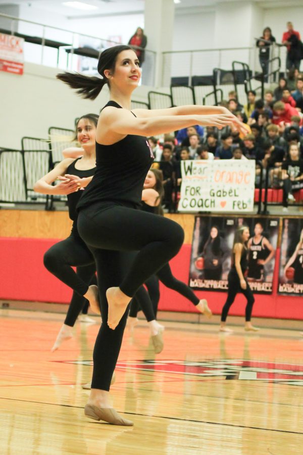Senior Lauren Szlosek watches the students cheering in the stands as she performs a turn with the other Marquettes.