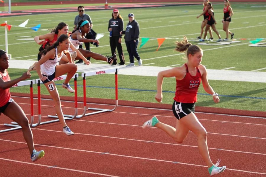 Senior Maddie Meiner (far right) is in the lead as she runs a hurdle event at a meet. 
