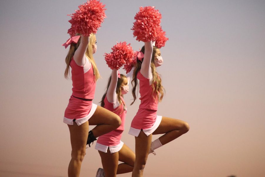 The cheer team shakes their pom poms while in stunts to hype up the crowd during the football game.