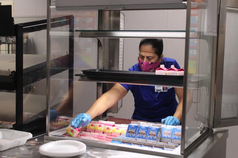 Cafeteria worker Maria Mestas restocks the beverage corner. The cafeteria has been short on drinks, among other items.