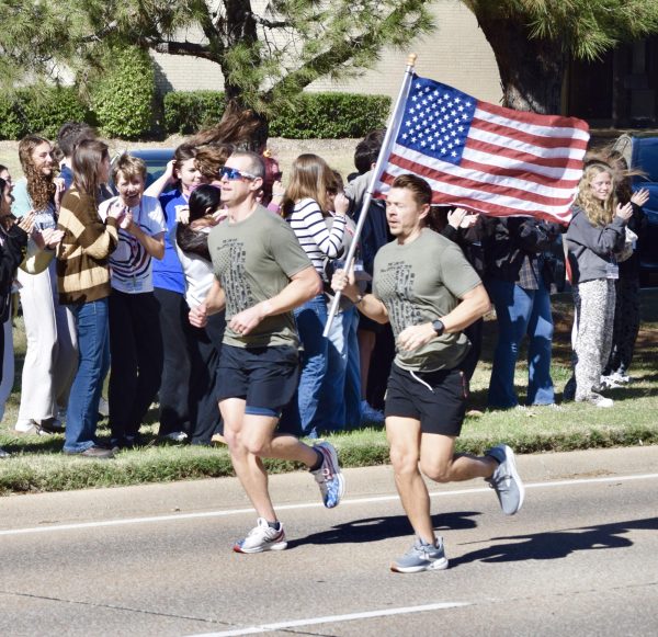 Runners participating in the 12th annual Veterans Day Relay Run sprint down Morriss Road passed cheering Marcus students on Tuesday, Nov. 11, 2025. Veterans and volunteer runners carried the American flag on a 32-mile course through Flower Mound to honor service members. The run starts and ends at the Flower Mound Community Activity Center each year, passing by local schools, the police department and fire stations along the way.